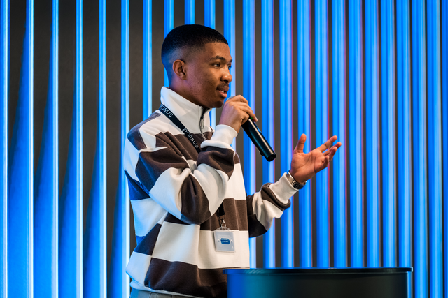 Iviwe speaking into a microphone at a Prosus event